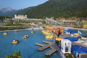 A water park with inflatable rafts, a wooden dock, and a small building with a red sign.
