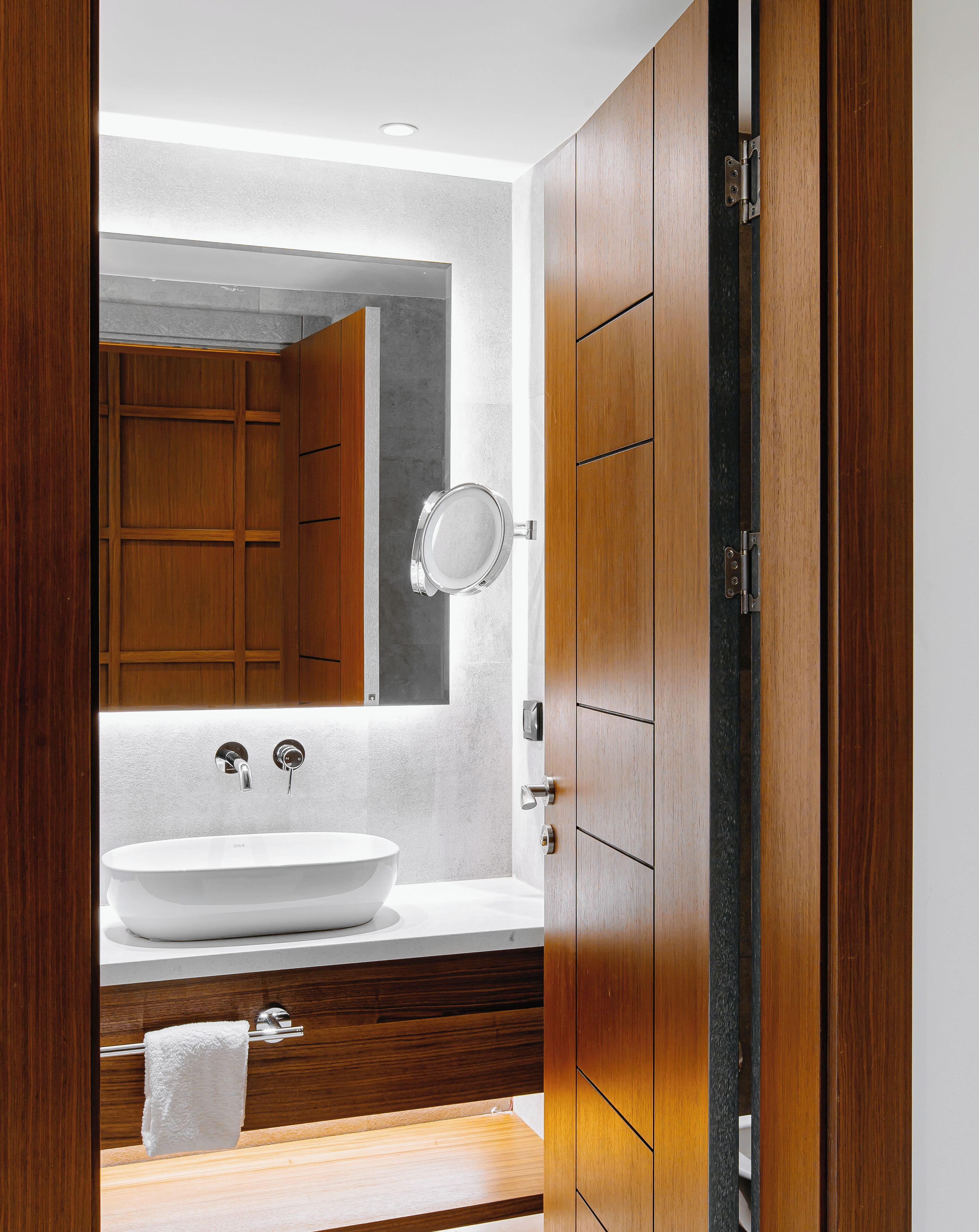 Un baño moderno con un lavabo grande, armarios de madera y un espejo.