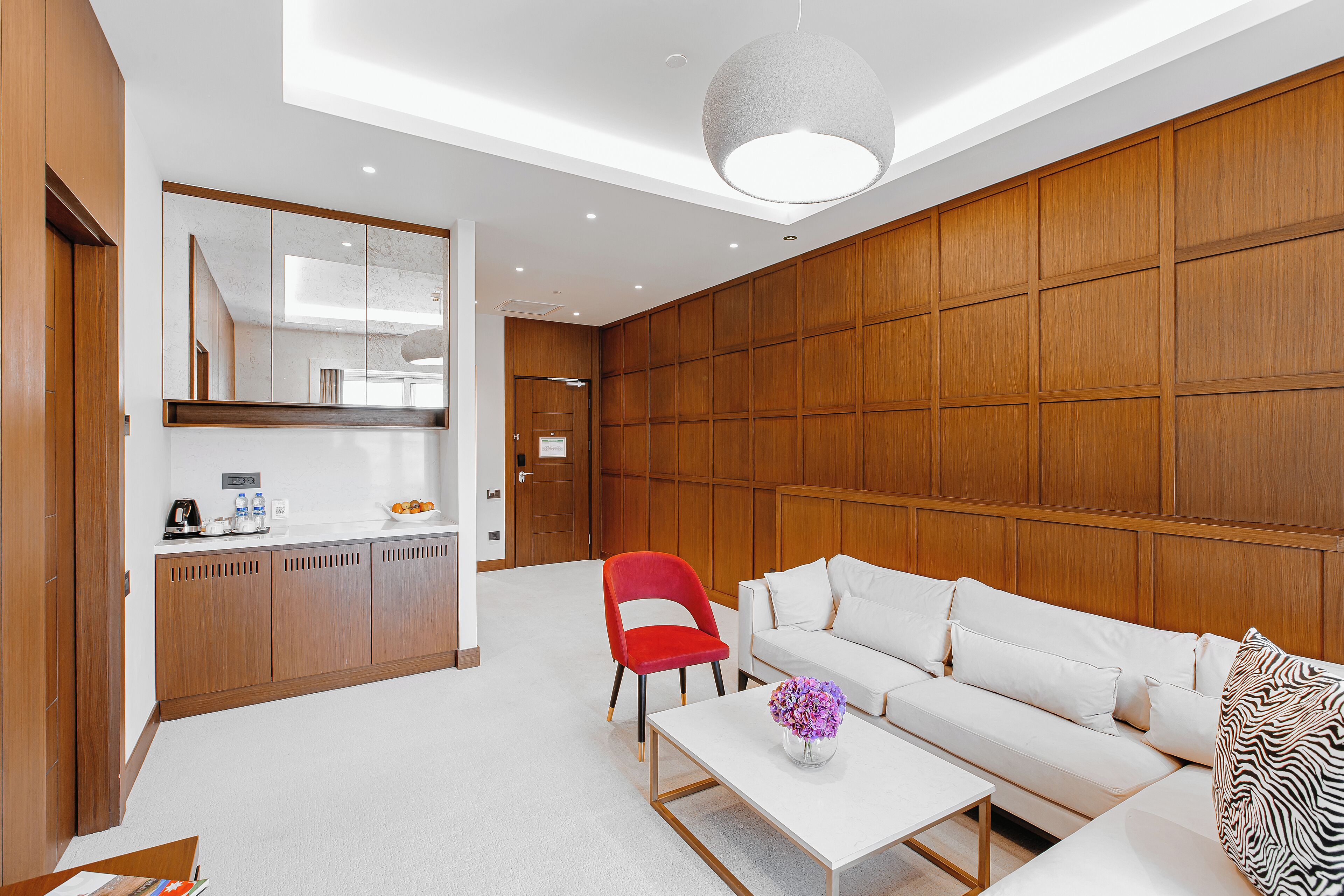 Una sala de estar moderna con un sofá blanco, un sillón rojo y una mesa de centro con un jarrón.
