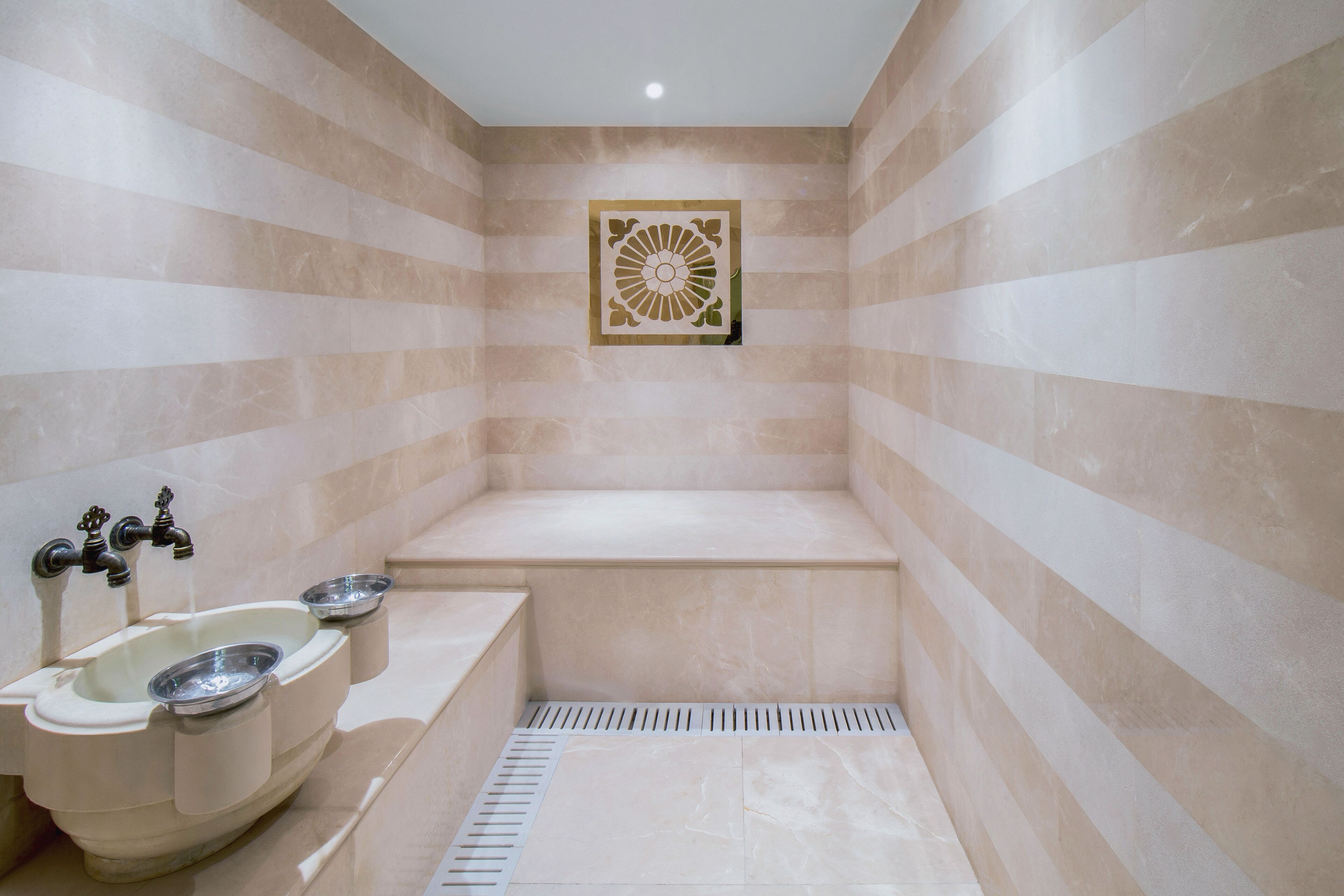 Une salle de bain moderne avec une baignoire sur pieds, un lavabo avec un receveur et un mur décoratif recouvert de carreaux.