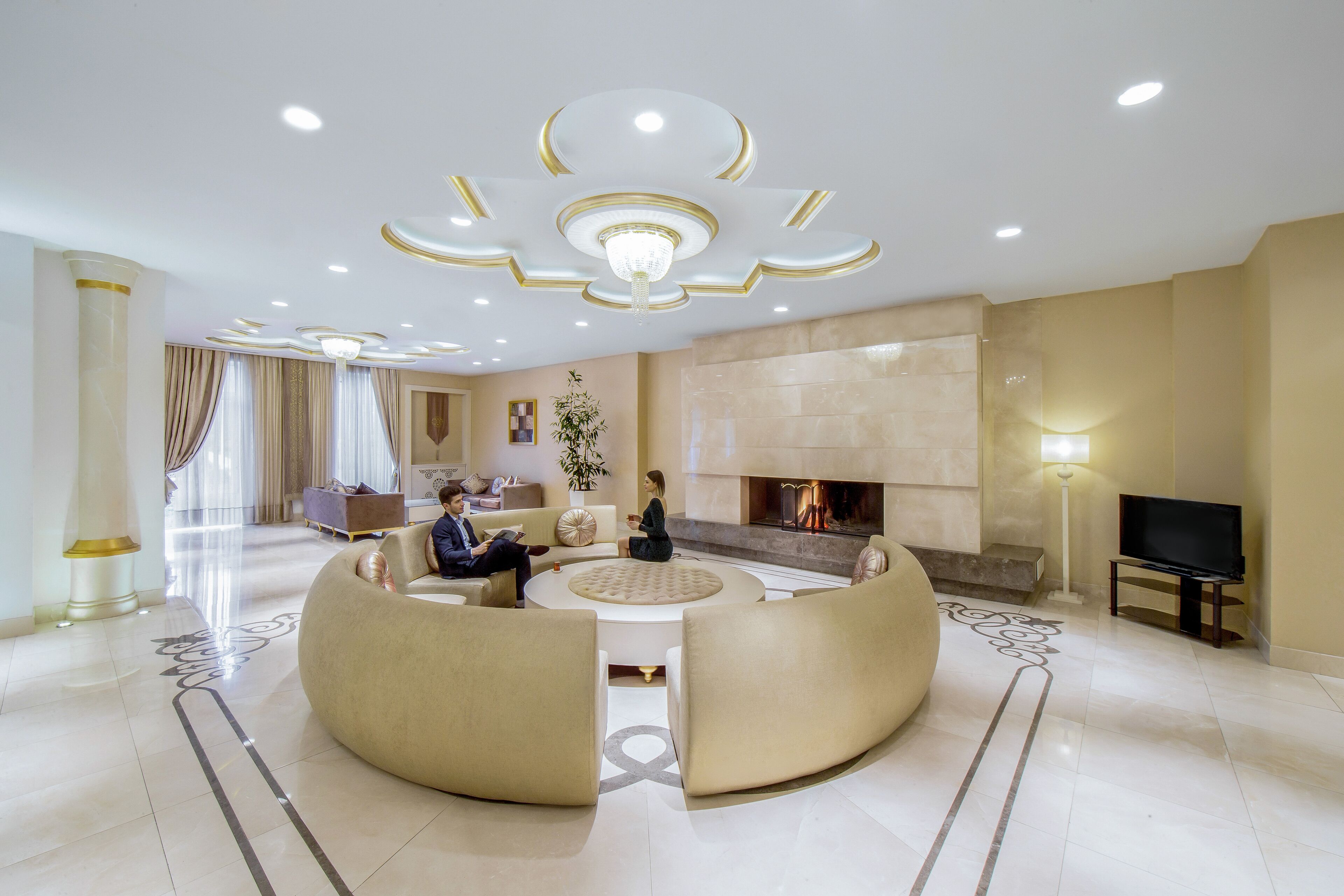 A spacious living room with a central seating area, a fireplace, and a television.