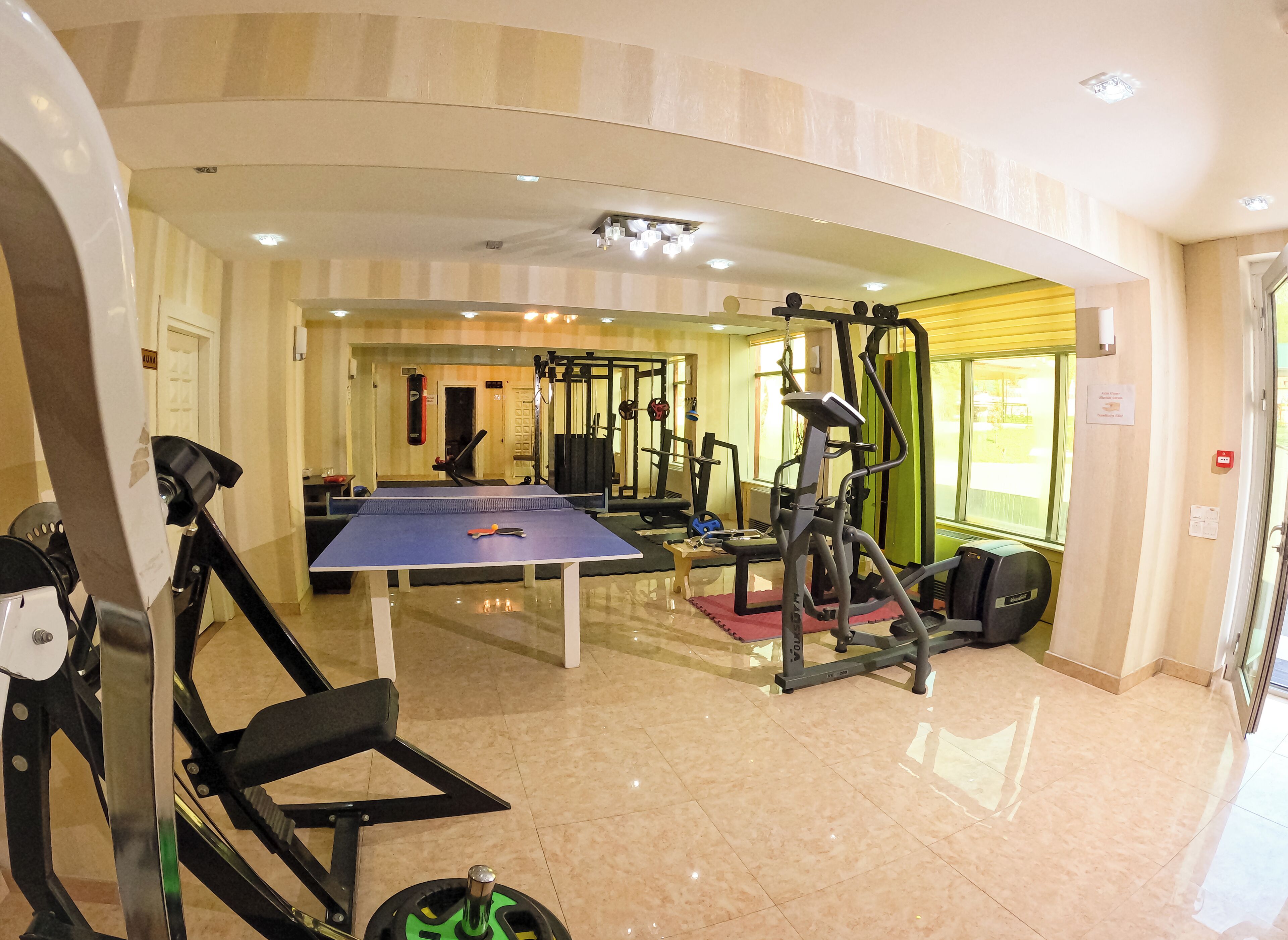 Un gimnasio con equipamiento de ejercicio, una mesa de ping pong y un saco de boxeo.