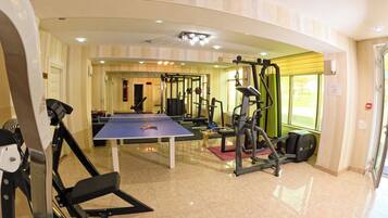 Un gimnasio con equipamiento de ejercicio, una mesa de ping pong y un saco de boxeo.