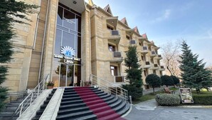 A hotel entrance with a grand staircase, a large banner, and a well-maintained garden area. -  Qebele Yeddı Gozel Hotel (Gabala)
