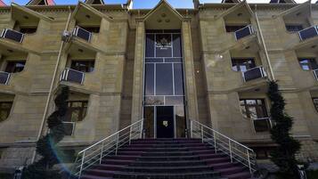 Un hotel de varios pisos con una entrada imponente, una escalera que conduce a la puerta principal y un cielo despejado.