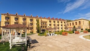A multi-story hotel with a courtyard, outdoor seating, and a pool. -  Qebele Yeddı Gozel Hotel (Gabala)