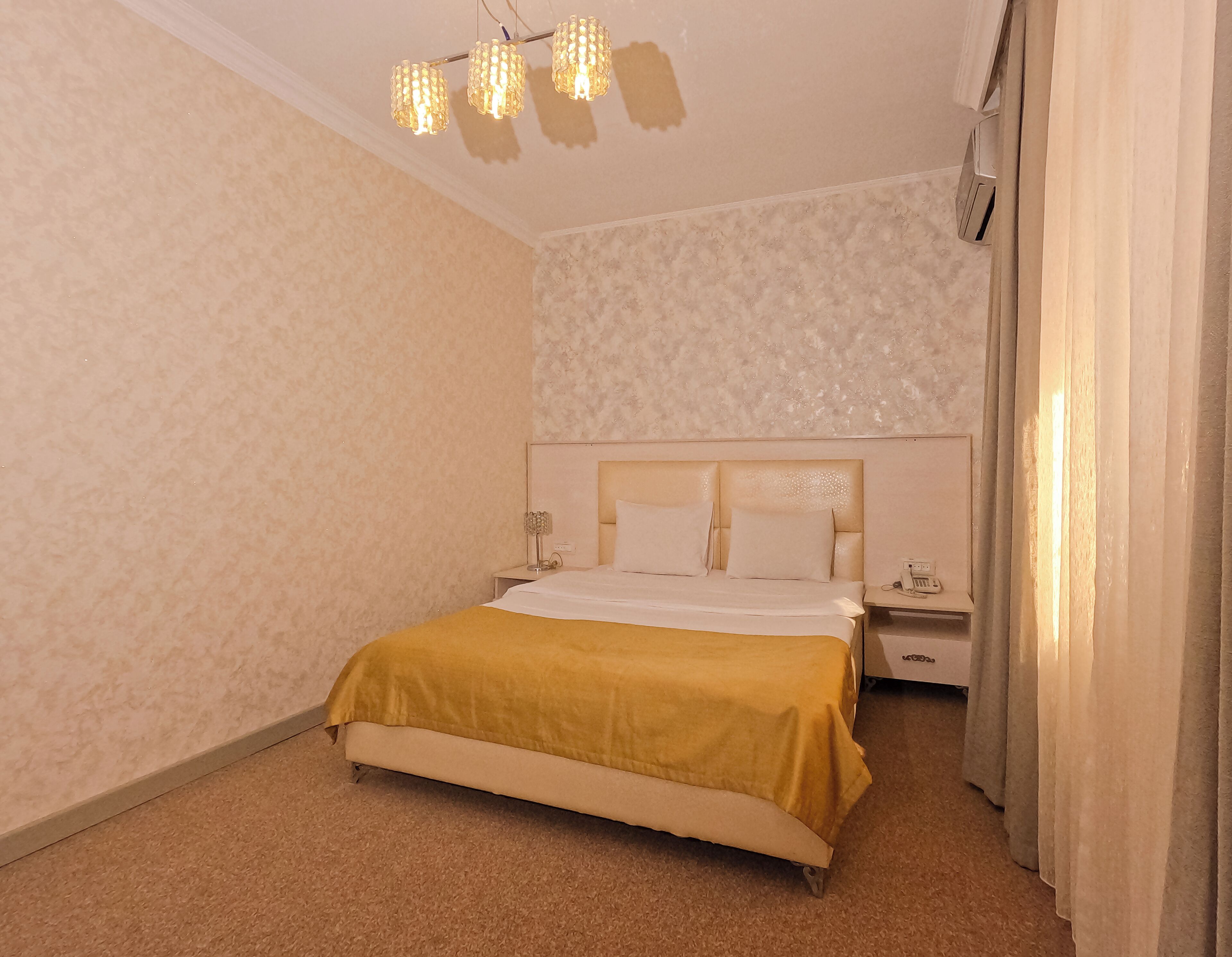 Ein Schlafzimmer mit Bett, Nachttischen, einer Lampe und einer Deckenleuchte.