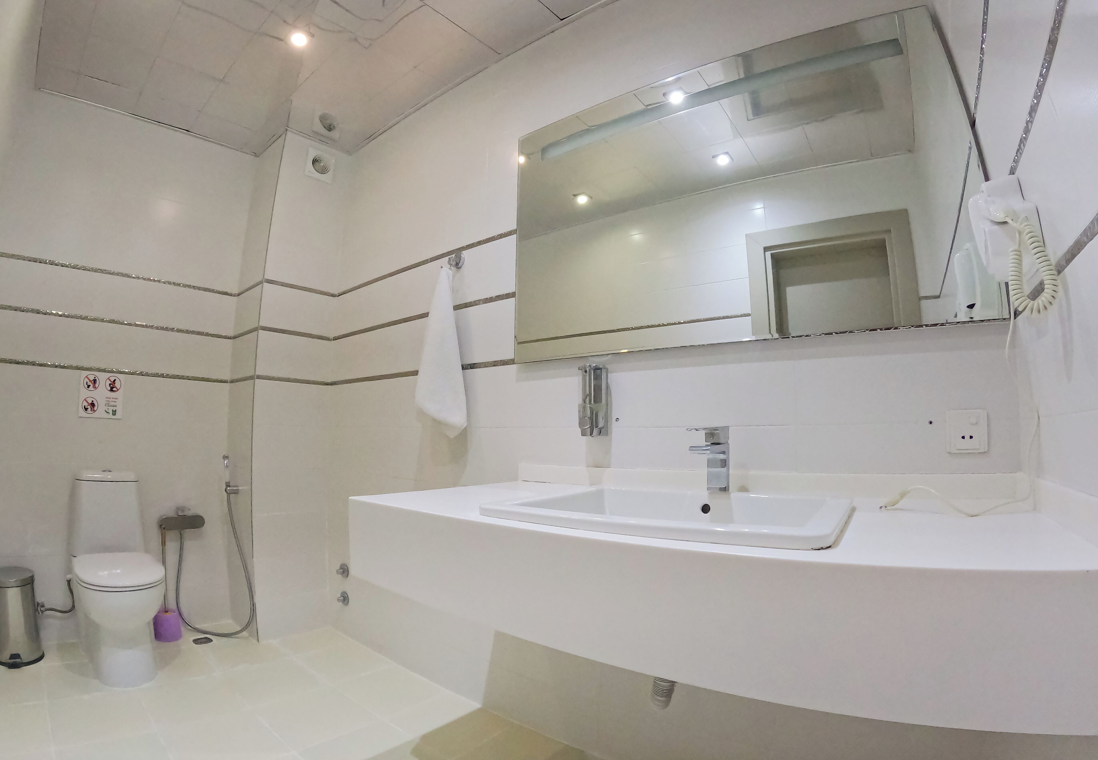 A modern bathroom with a white sink, a large mirror, and a shower.