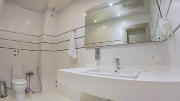 A modern bathroom with a white sink, a large mirror, and a shower.