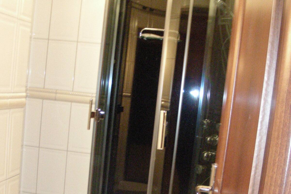 A bathroom with a glass-enclosed shower, a white toilet, and a white bathtub.
