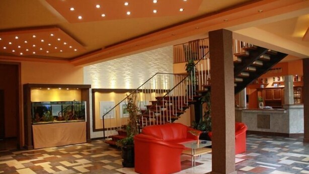 Un hall d’entrée spacieux avec un sol à carreaux, un escalier et un espace d’accueil.