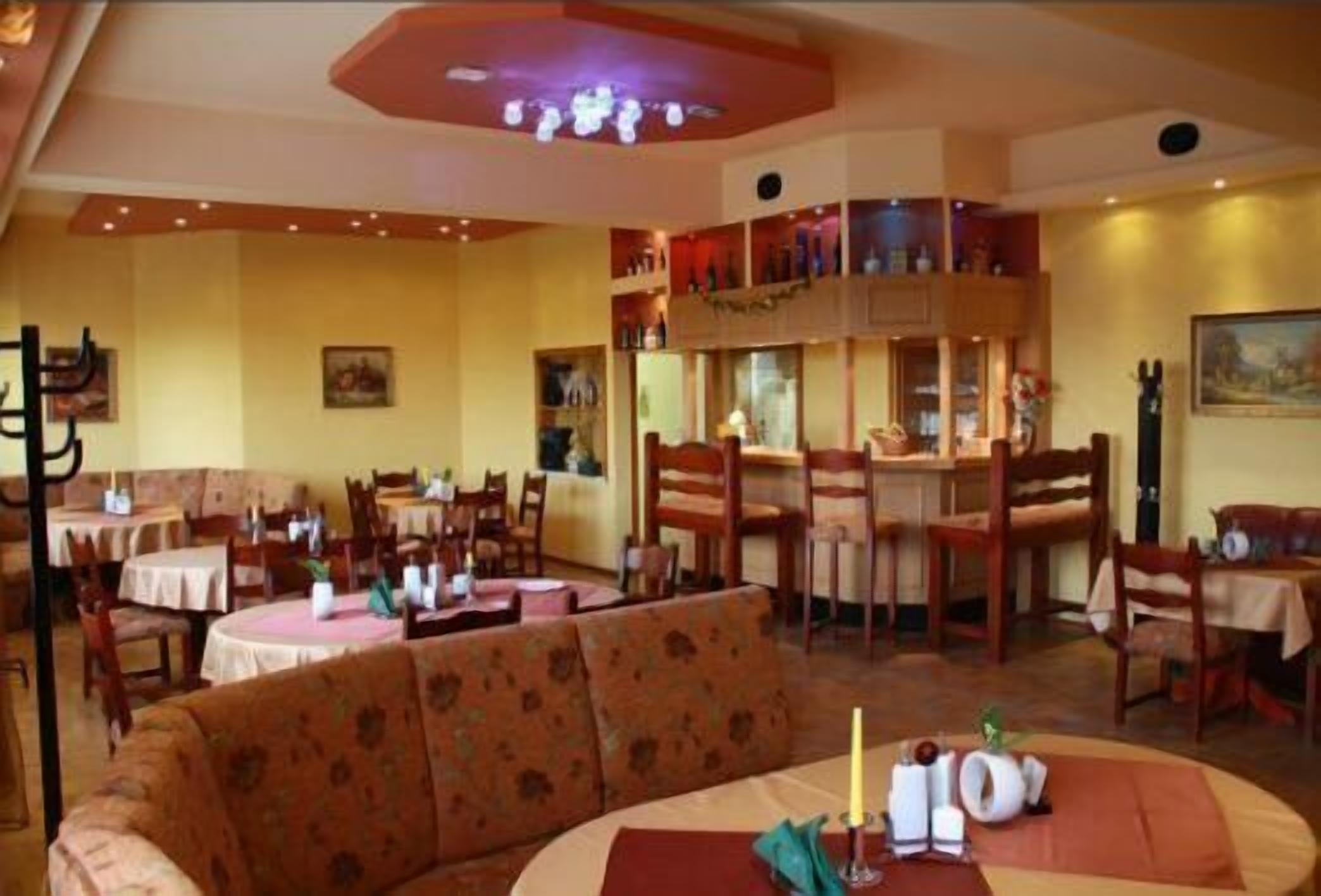 En restaurang med runda bord, trästolar och en central sittgrupp med en soffa.
