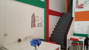 Quarto com escada, mesa com um vaso de flores e arte nas paredes retratando pontos turísticos de Londres.