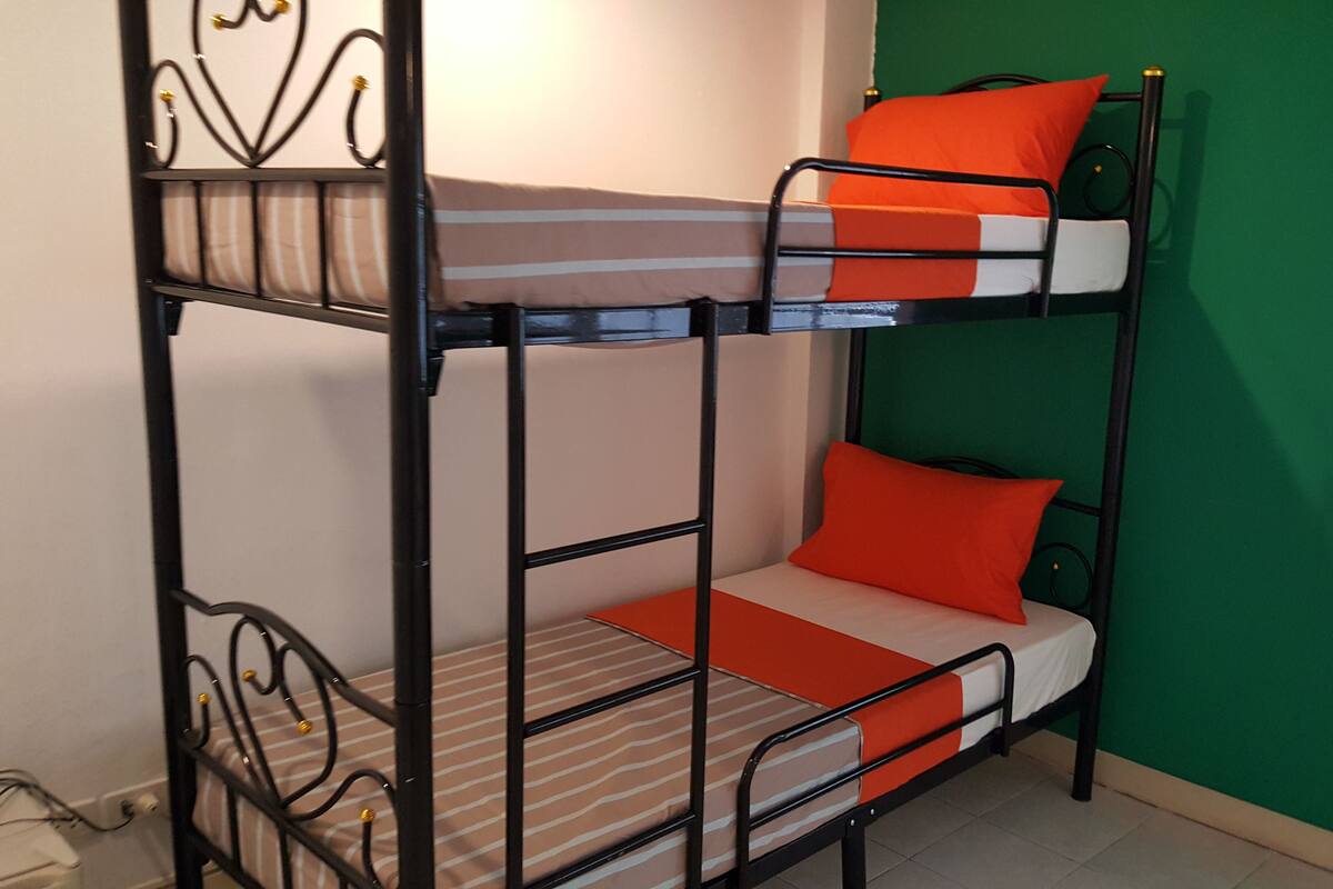 A bunk bed with orange pillows and striped bedding.