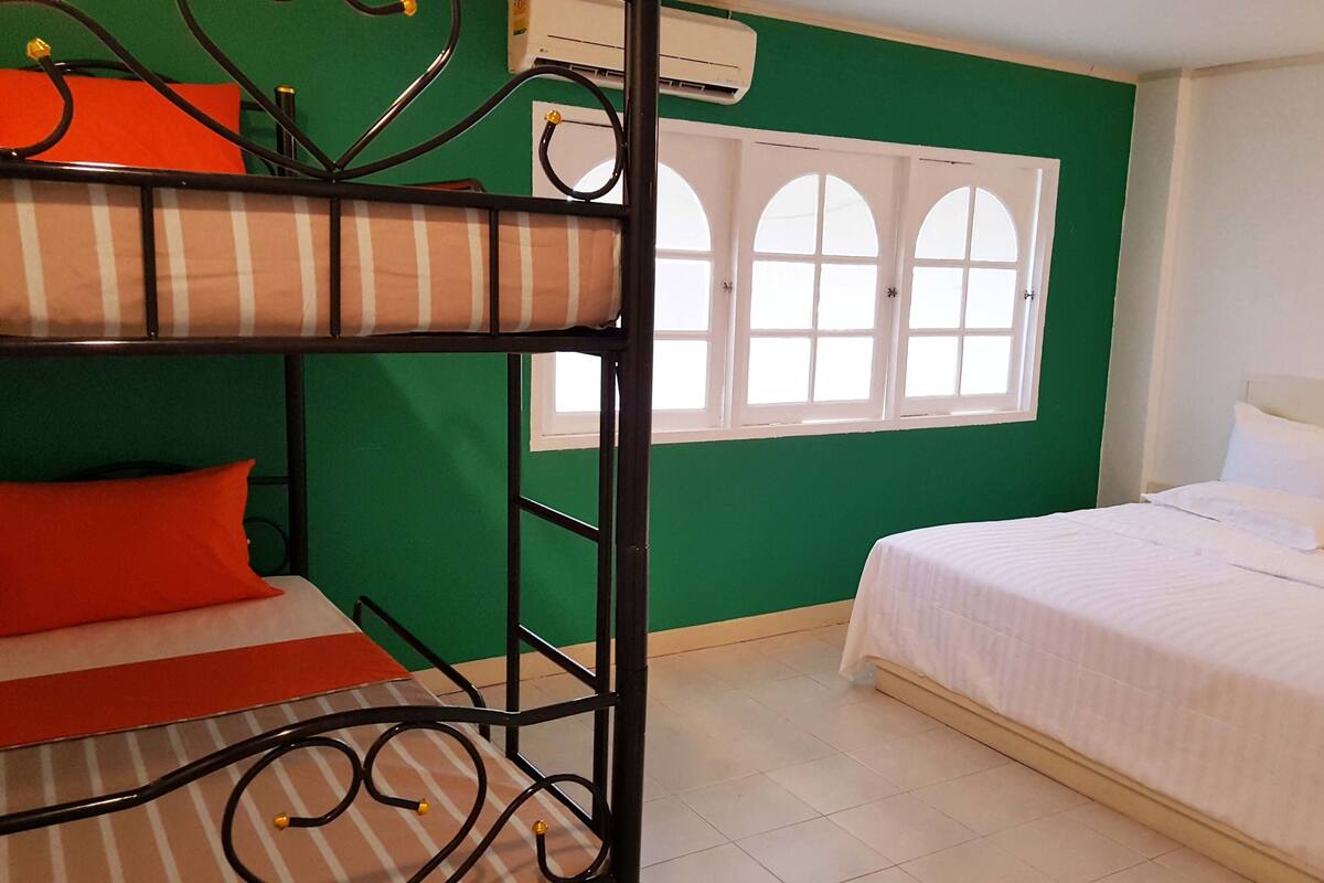 A room with a bunk bed, a single bed, and a window with arched tops.