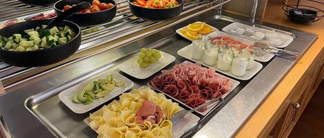 Un bufé con diversas opciones de comida, como frutas, verduras, quesos, carnes y salsas.