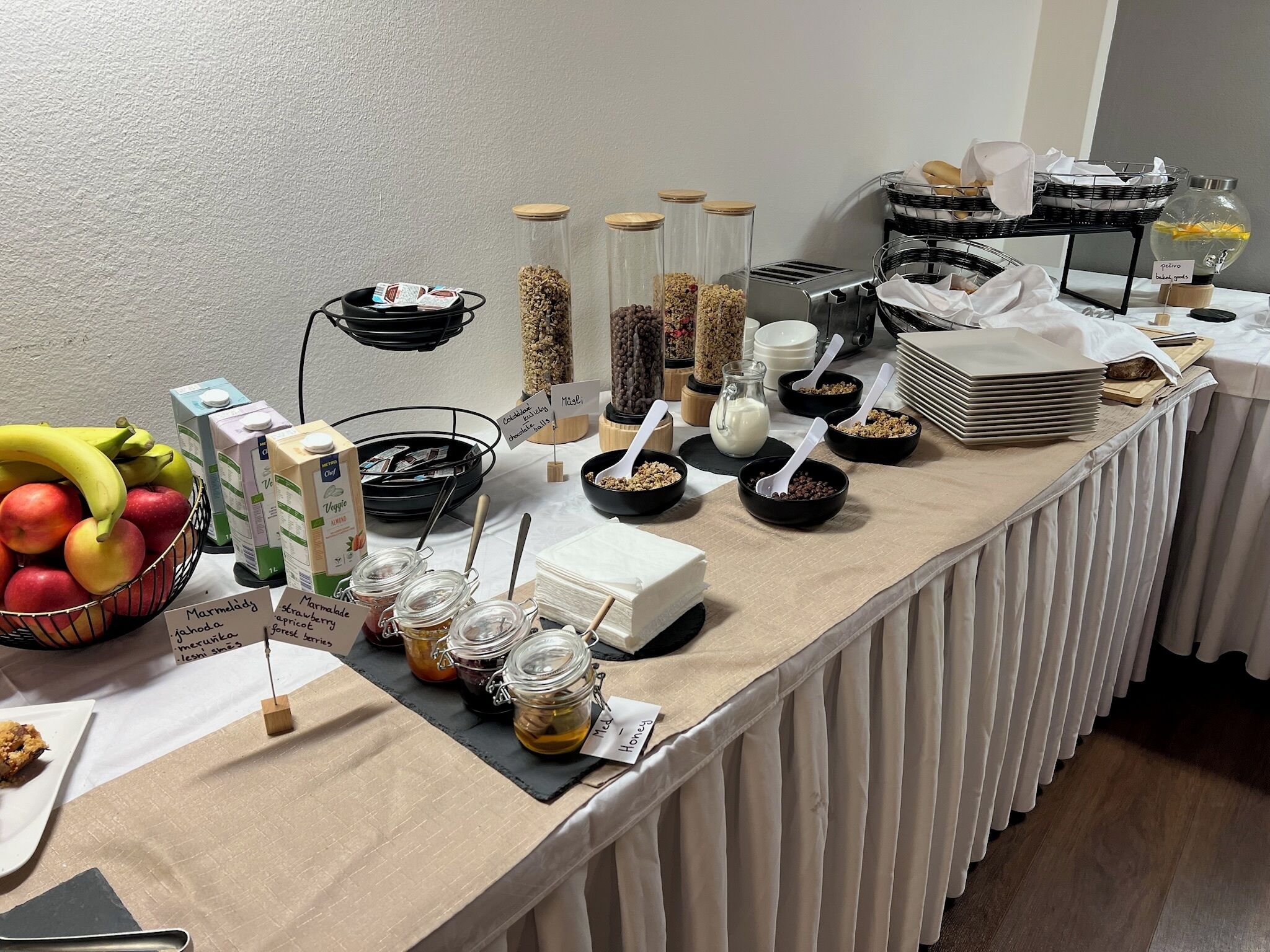 Une table de buffet proposant une variété d’aliments, notamment des fruits, des céréales et des condiments.