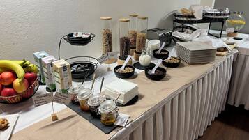 Une table de buffet proposant une variété d’aliments, notamment des fruits, des céréales et des condiments.