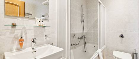 A modern bathroom with a glass-enclosed shower, a white sink, and a toilet.