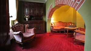 Una habitación con muebles antiguos, una escalera y una alfombra roja.