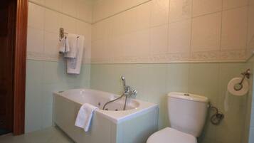 A bathroom with a bathtub, toilet, and a towel rack.