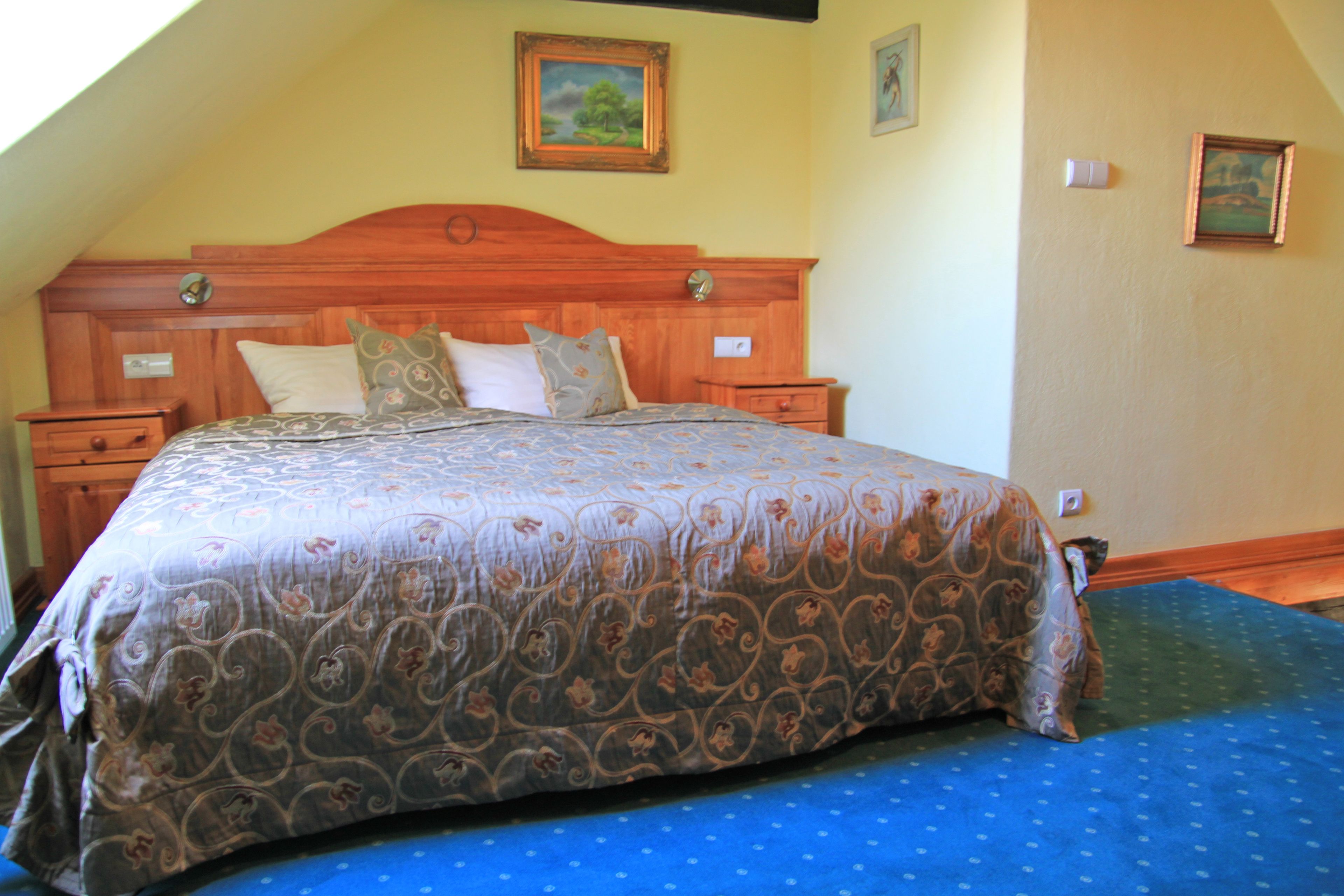 A bedroom with a wooden headboard, a patterned bedspread, and two bedside tables.