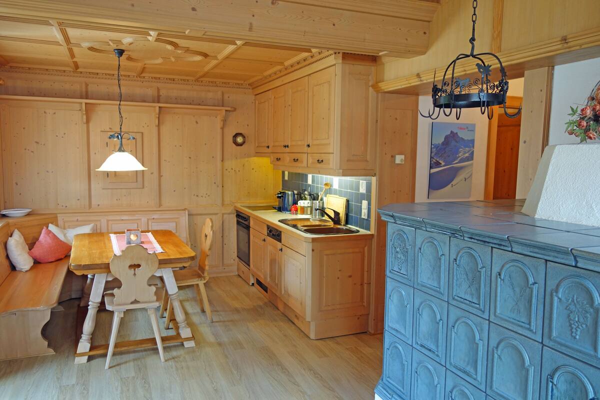 A wooden kitchen with a wooden table and bench, a sink, and a blue cabinet.