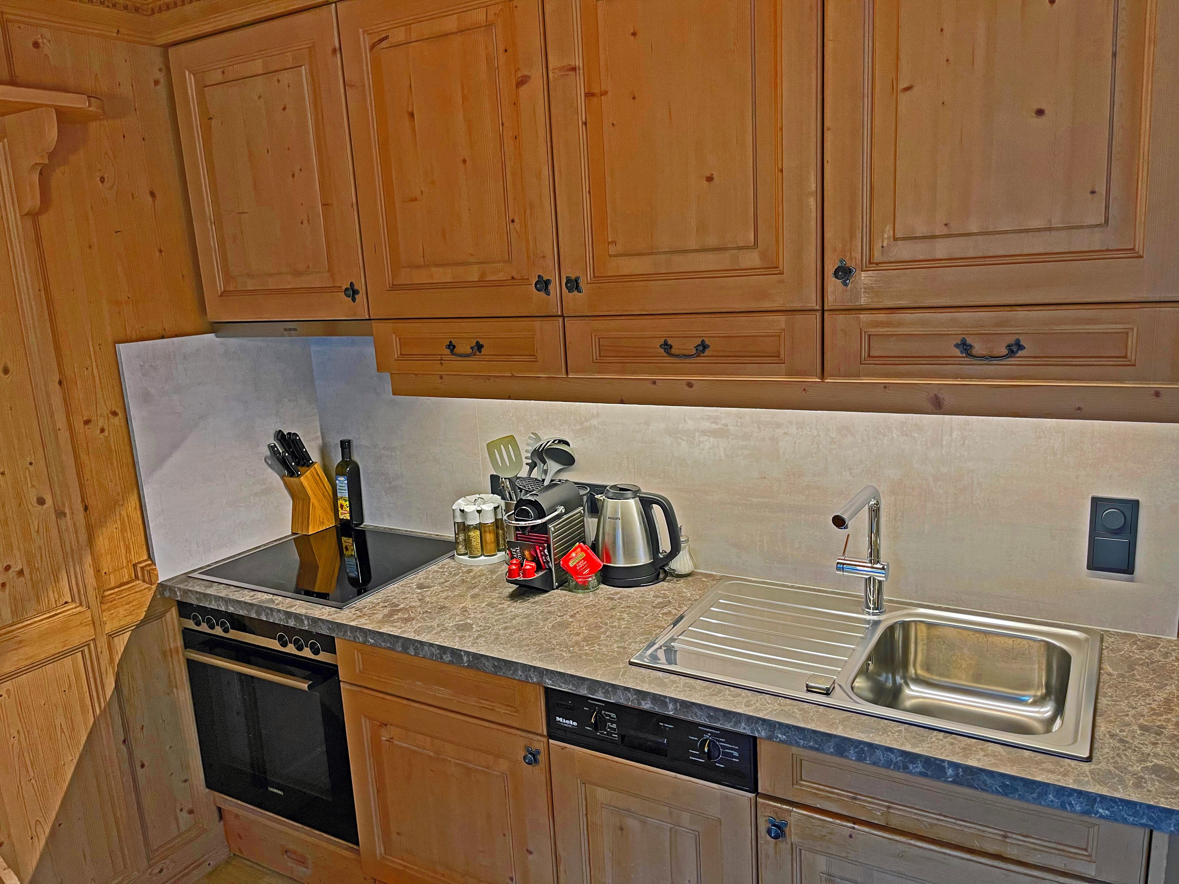 A kitchen with wooden cabinets, a stainless steel sink, and a dishwasher.