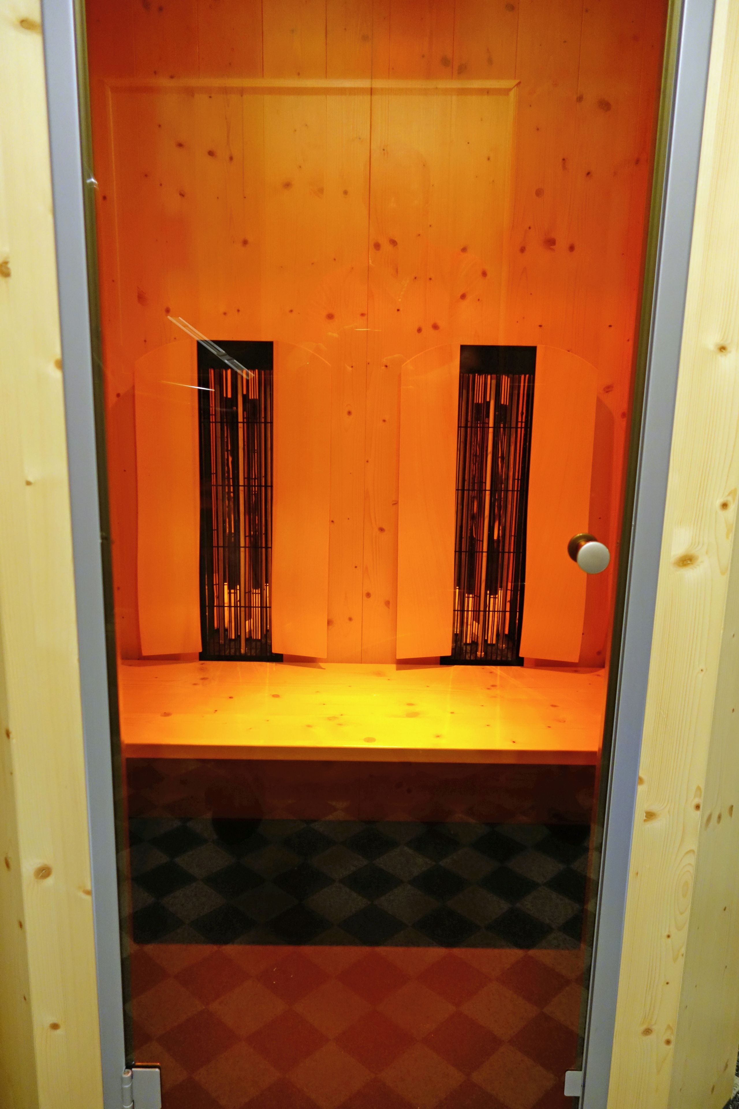 A small, enclosed room with wooden walls and a checkered floor.