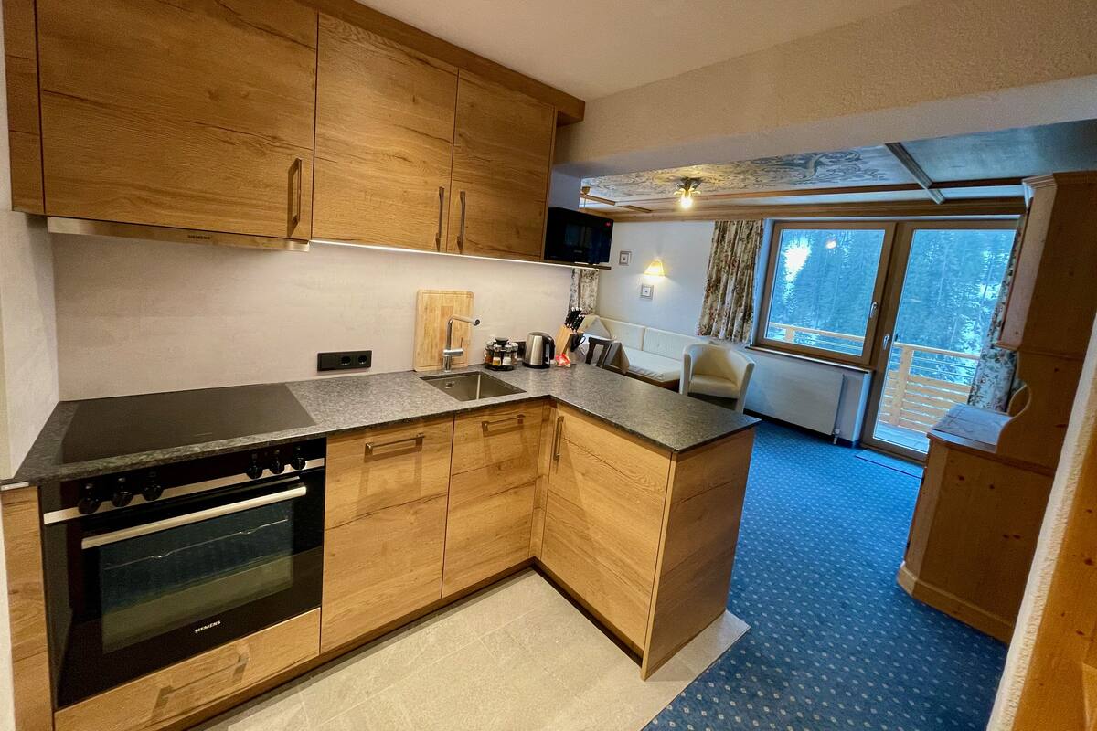 A modern kitchen with wooden cabinets, a built-in oven, and a large island with a sink.