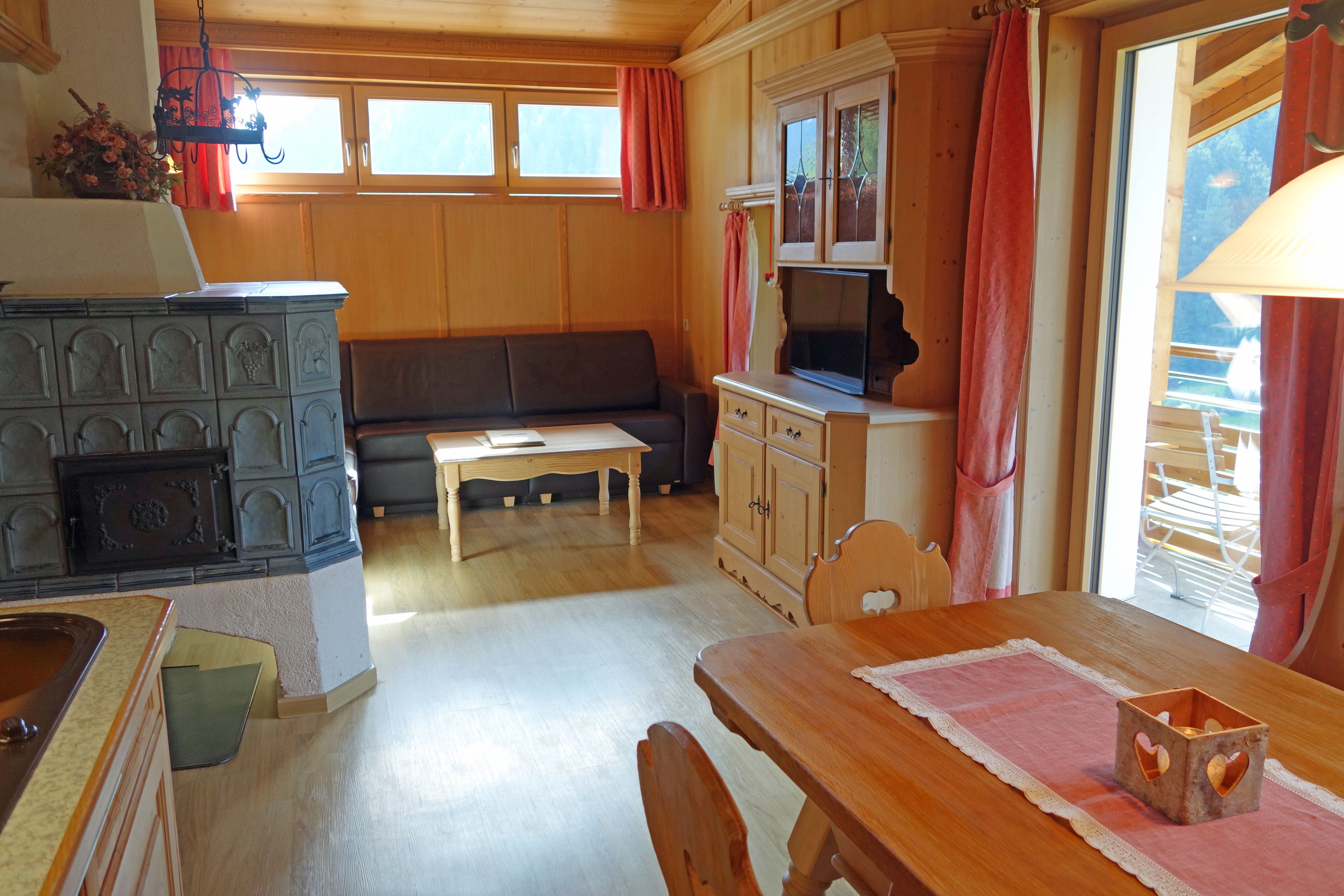 A cozy room with a wooden dining table, a sofa, a television, and a fireplace.