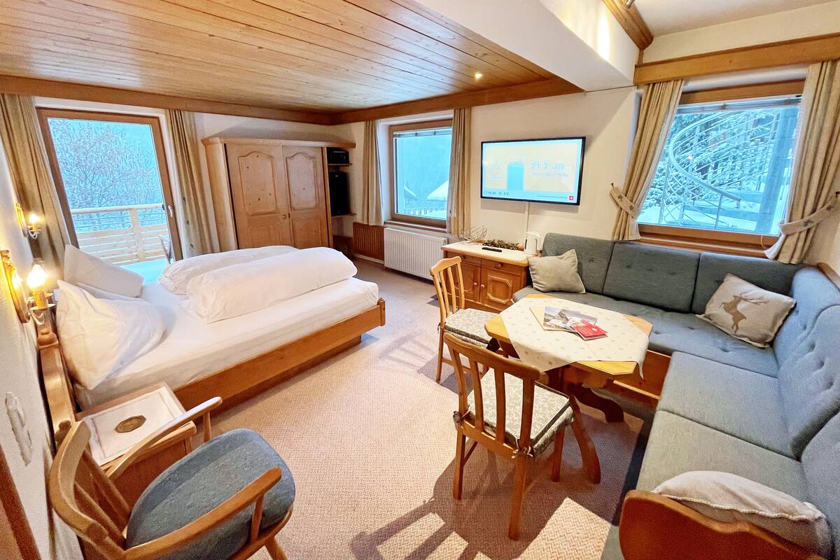A cozy cabin room with a bed, sofa, dining table, and a TV.