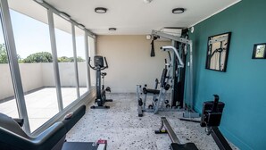 Une salle de sport équipée de matériel d’exercice, d’un tapis de course et d’un miroir au mur.