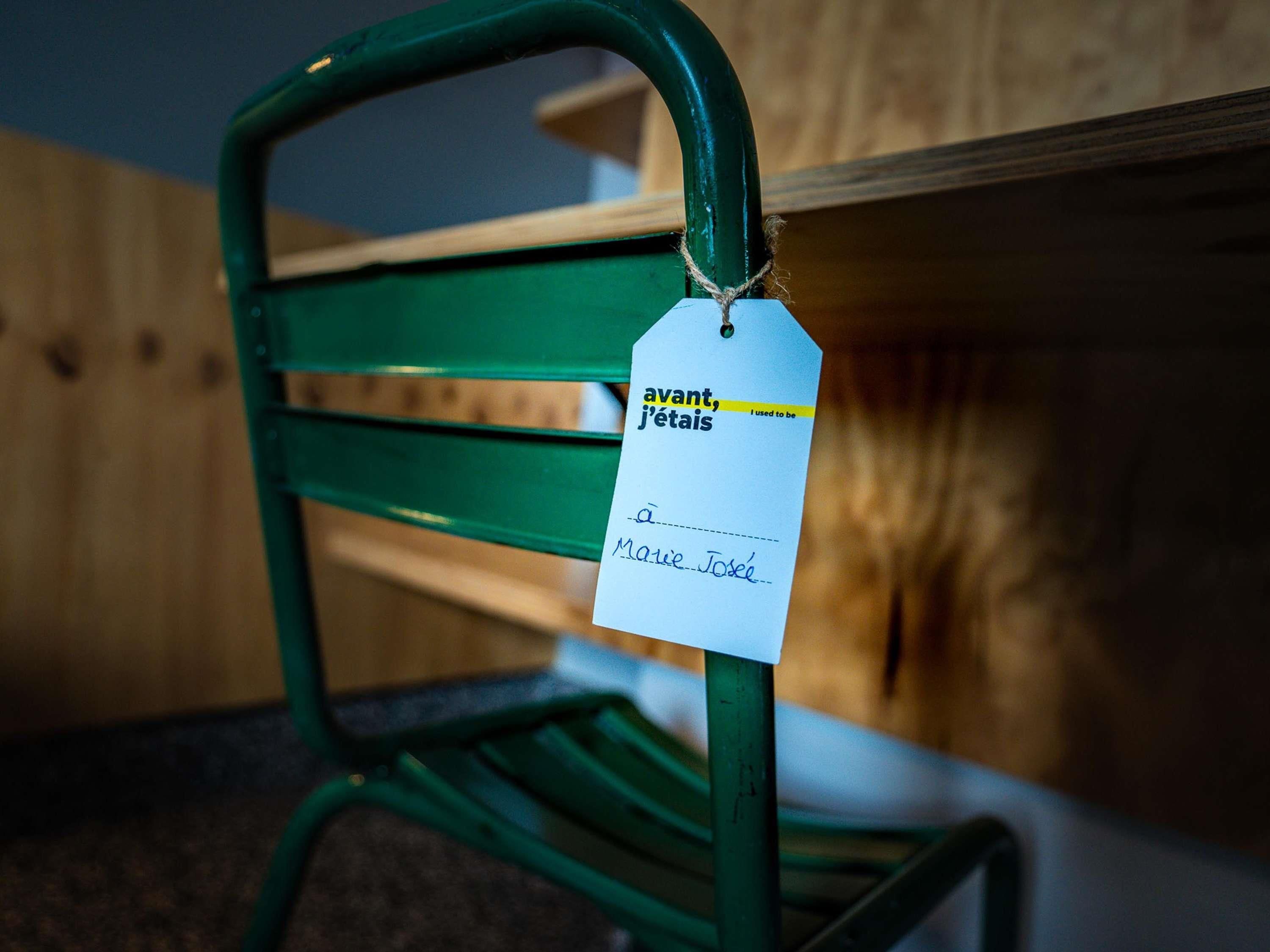A green metal chair with a tag attached to its backrest.