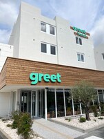 Un bâtiment moderne, avec une enseigne « Greet Hotel », de grandes fenêtres et une façade en bois.