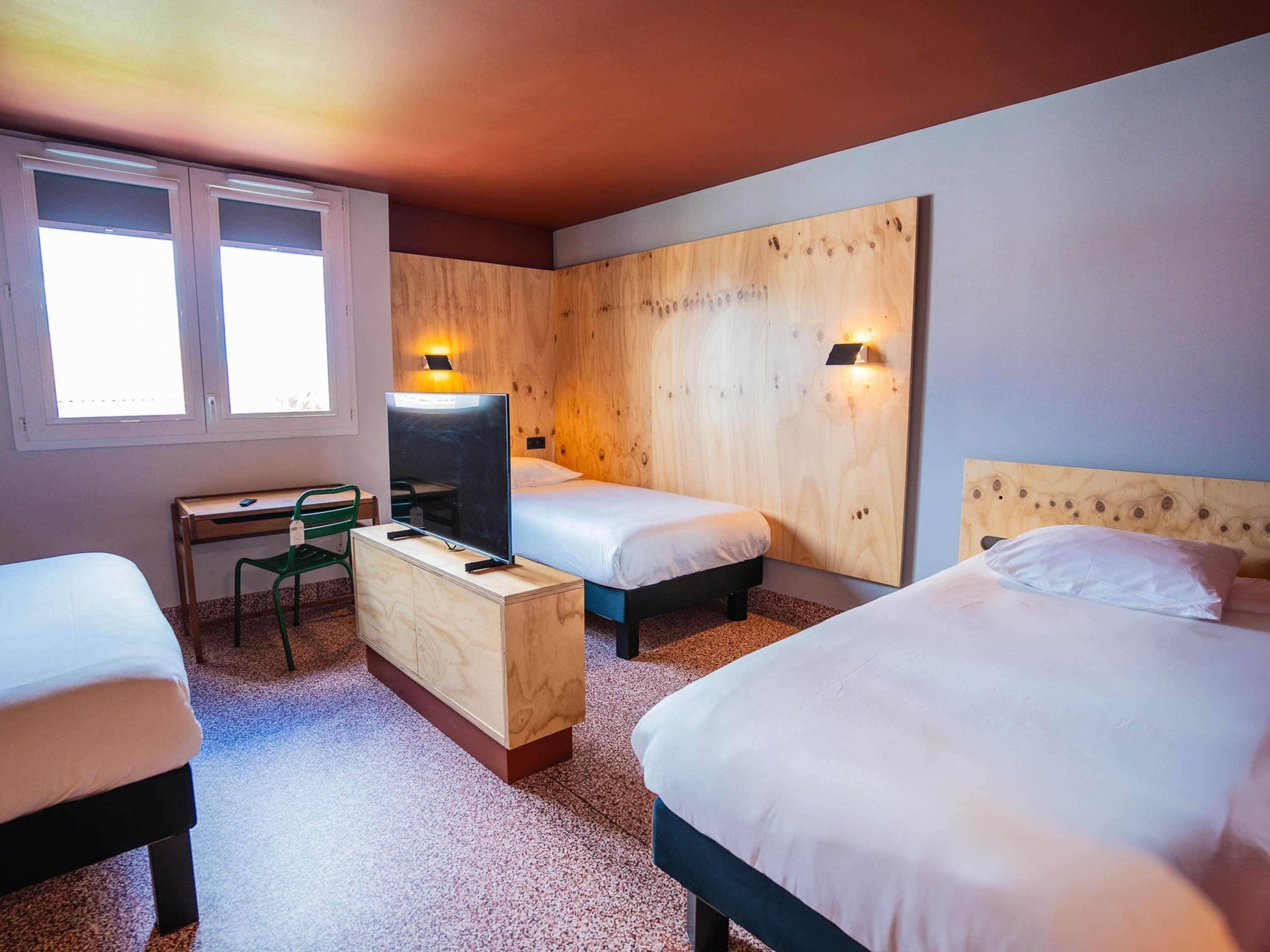 Habitación de hotel con dos camas, un escritorio, una silla y un televisor.