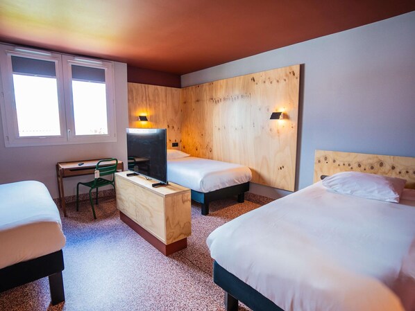 Habitación de hotel con dos camas, un escritorio, una silla y un televisor.