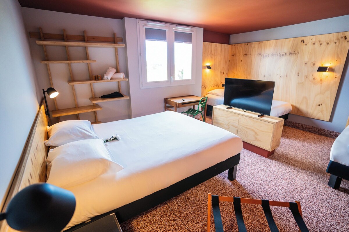 Un dormitorio con cama, escritorio, silla, televisor y estante.