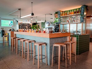 Zona de bar con taburetes, una barra y un panel con la carta.