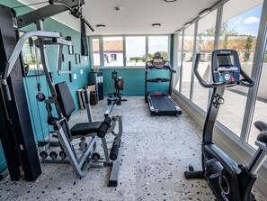 Un gimnasio con máquinas de cardio, equipo de levantamiento de pesas y una cinta de correr.