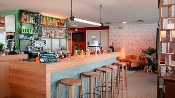 A bar area with stools, a coffee machine, and shelves with bottles and glasses.