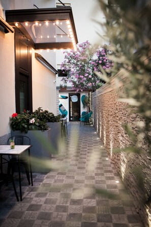 Un patio al aire libre con suelo estampado, pared de ladrillo y zona de estar con sillas y una mesa.