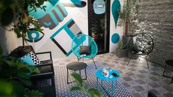 Un área de estar moderna al aire libre con suelo estampado, un mural y un letrero de casa de huéspedes.