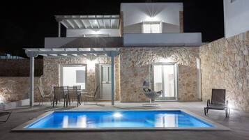 Relax in a serene outdoor space with a covered patio and second-floor balcony overlooking the property.