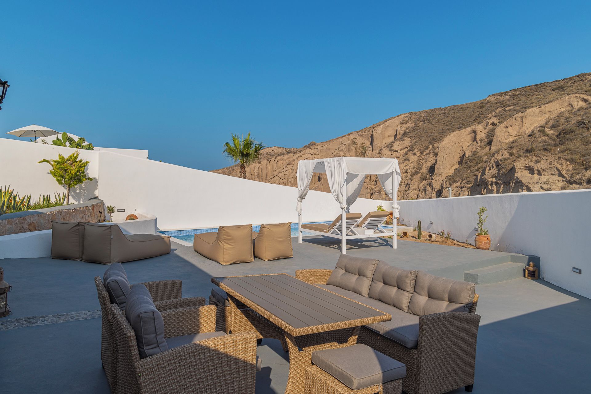 Un área de estar al aire libre con mobiliario de mimbre, una piscina y vistas a las montañas.