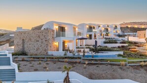 Un resort moderno con edificios blancos, muros de piedra y zonas de estar al aire libre.