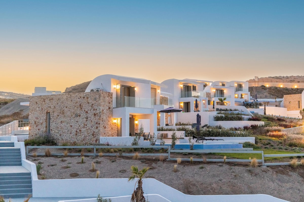 Ein modernes Resort mit weißen Gebäuden, Steinmauern und Außenbereichen mit Sitzgelegenheiten.