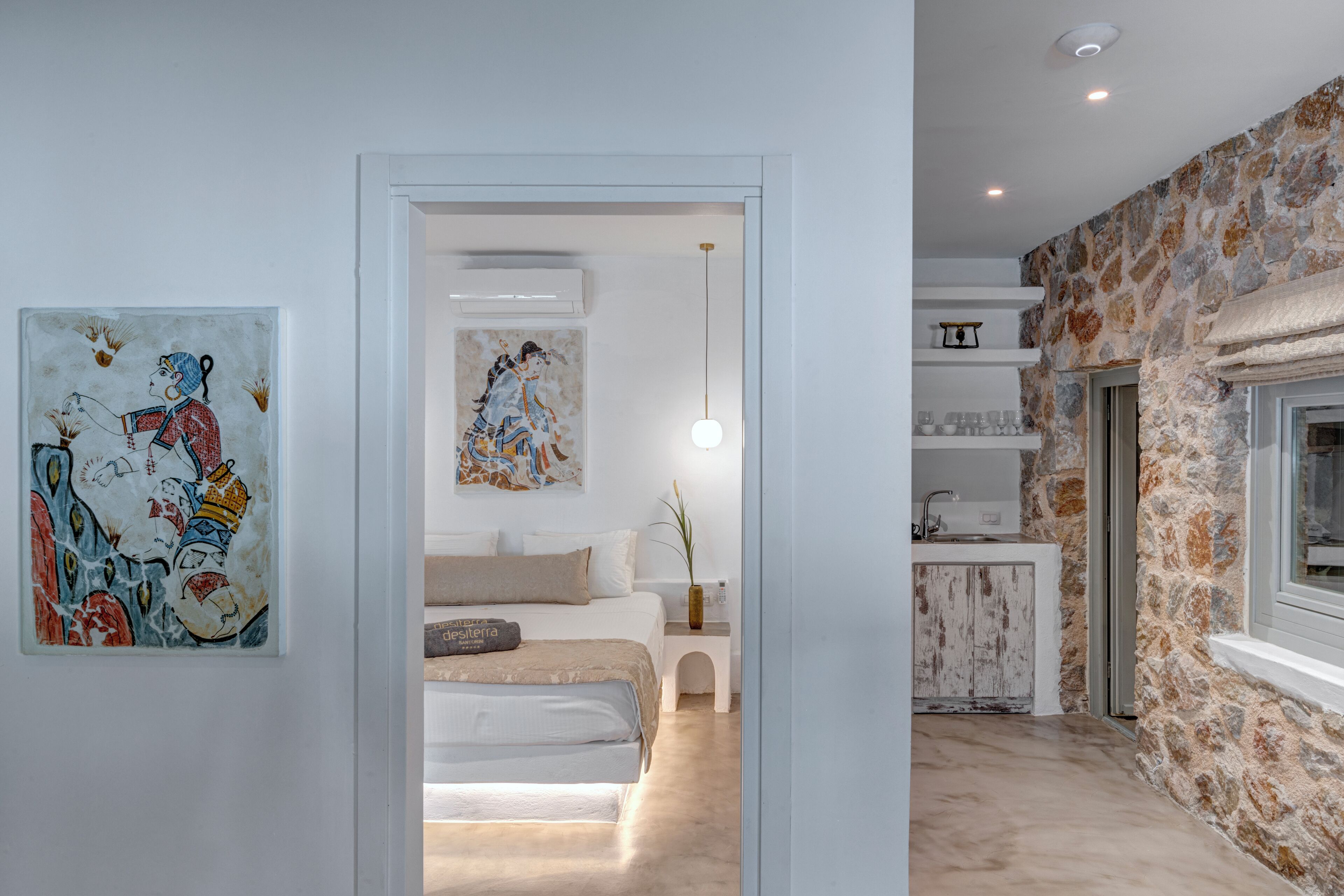 Un interior moderno con una cama, obras de arte, una pared de piedra y una zona de cocina.