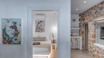 A modern interior with a bed, artwork, a stone wall, and a kitchen area.