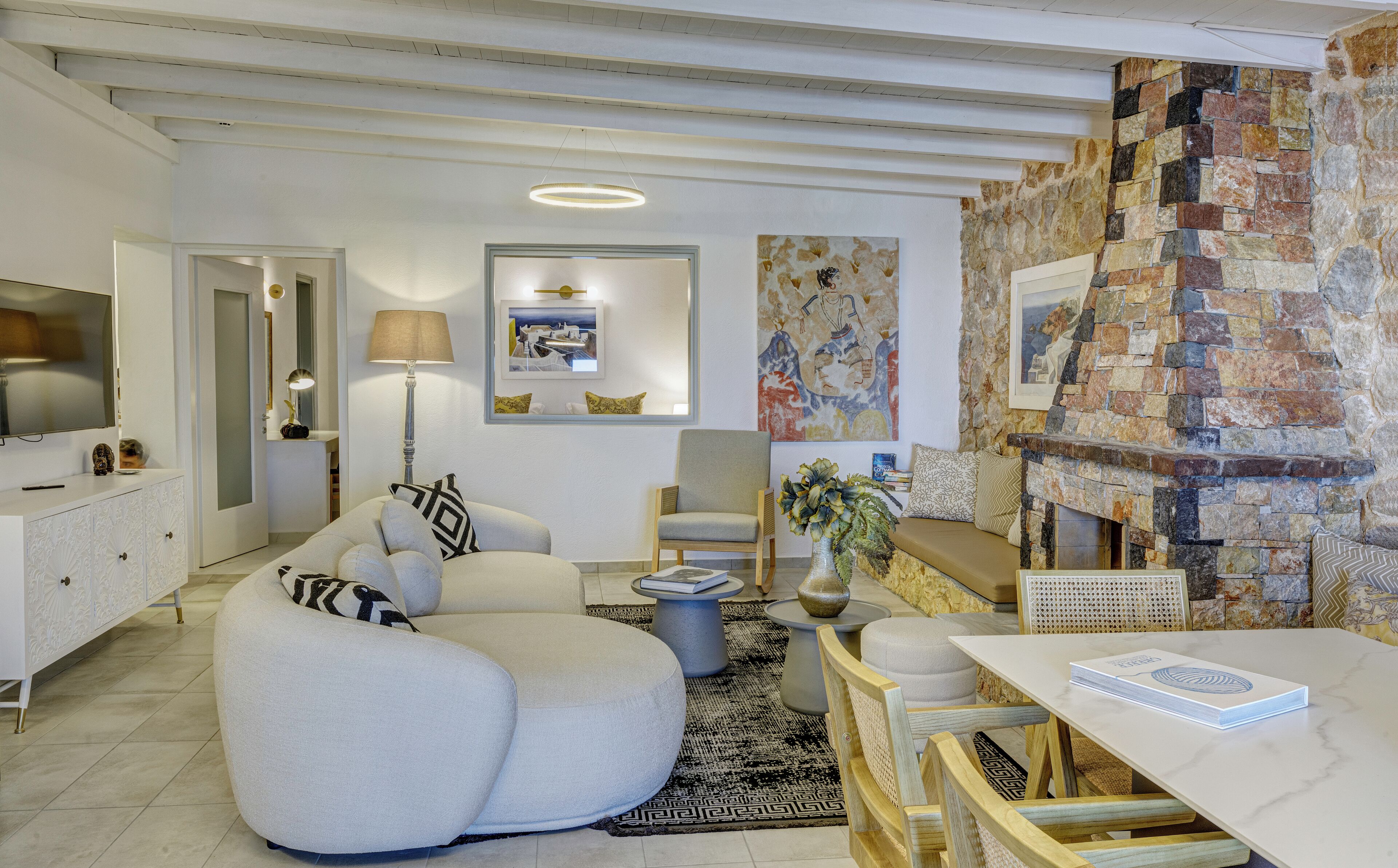 A modern living room with a curved sofa, a dining area with a table, and a stone accent wall.